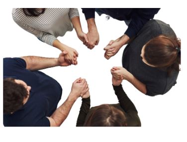 a view from above of five people standing in a circle with joined hands