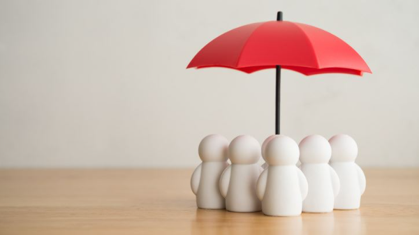 Image of a group of toylike individuals huddled under an umbrella.