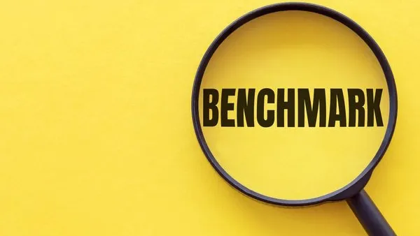The word BENCHMARK is written on a magnifying glass on a yellow background.