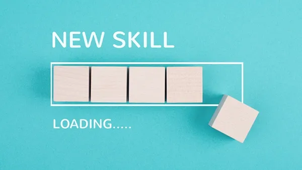 Photo of a teal background with wooden blocks arranged like a progress bar and one block offset to the right, with white text reading “NEW SKILL” above and “LOADING…..” below.