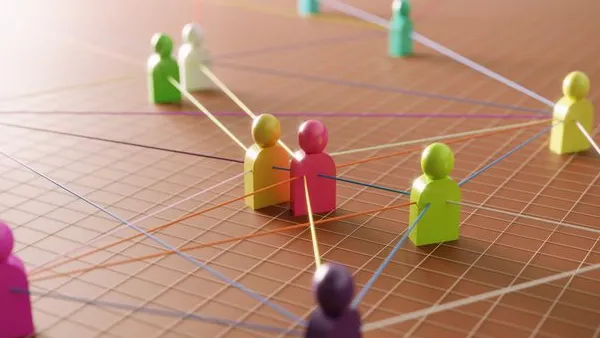 Illustration of colorful human-shaped figures connected by intersecting lines on a grid surface, representing networking or collaboration. The figures are in various colors, including pink, green, yellow, and purple, with lines forming a web-like structure to symbolize interconnected relationships or teamwork.