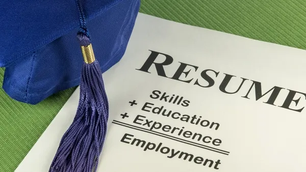 A graduation cap resting on a resume that highlights skills, education, and experience.