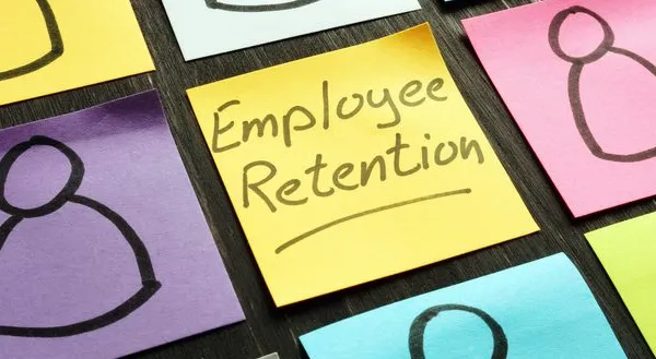 Photo of colorful sticky notes on a desk, each with a simple outline of a person. A yellow sticky note in the center reads “Employee Retention.”