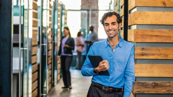 Man smiling with a laptop in his arm