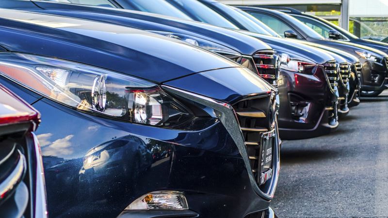 A row of freshly manufactured cars on lot for inspection