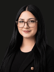 Professional photo of Naomi. She is a young woman with dark hair. She is dressed in business professional attire.