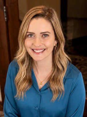 Erica Arvidson, a woman wearing a teal blouse against a dark backdrop