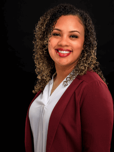 Professional photo of Brittany. She is a young woman with dark hair. She is dressed in business professional clothes and smiling.