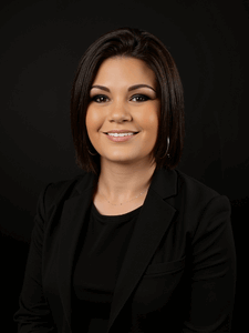 Professional photo of Holly, a woman with dark colored hair. She is dressed in business professional clothes. 