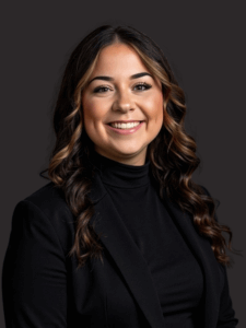 Professional photo of Kaylee. She is a young woman with dark hair. She is dressed in business professional clothes. 