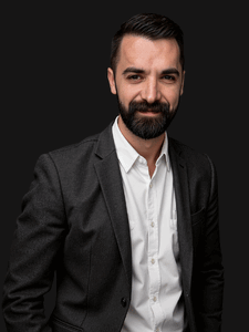 Professional photo of Aaron. He is a young man with dark hair. He is dressed in business professional clothes. 