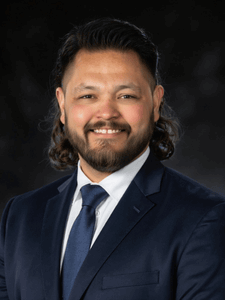 Professional portrait of John. He is smiling and dressed in business professional attire.